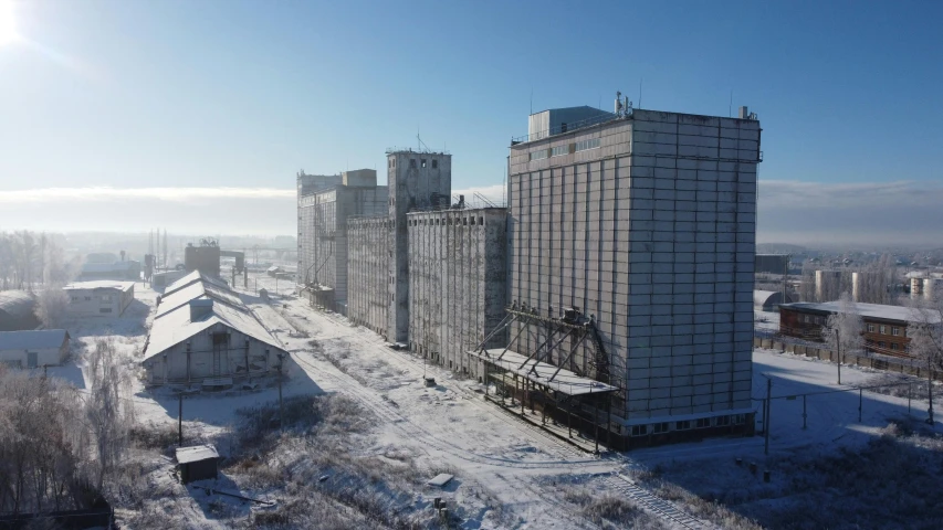 a large building sitting on top of a snow covered field, a portrait, silo, russia in 2 0 2 1, shipyard, snacks