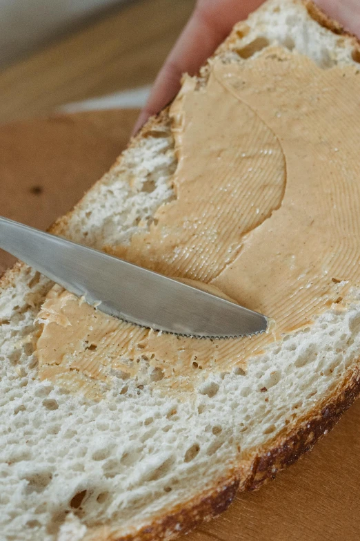 a person is spreading peanut butter on a piece of bread, inspired by Richmond Barthé, holding knife, beige, uncrop, super detailed image