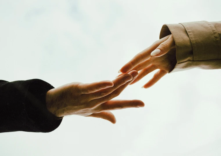 a close up of two hands reaching for each other, still photograph