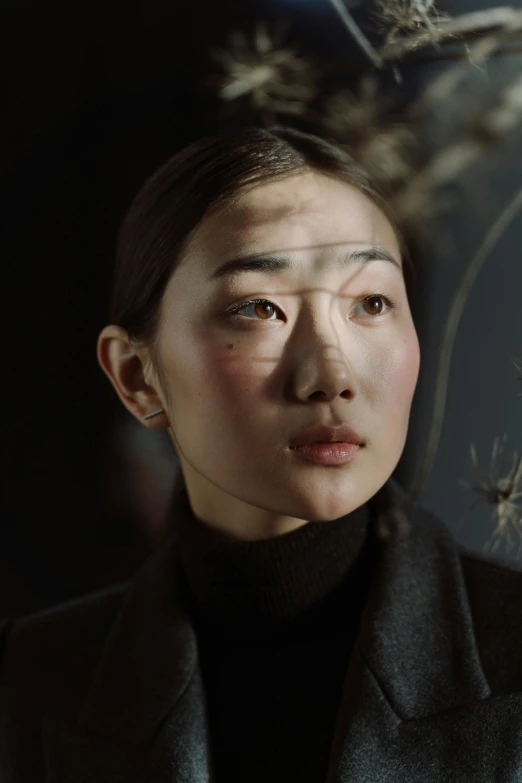 a woman standing next to a tree in a dark room, inspired by Fei Danxu, hyperrealism, markings on her face, still from the film, glass oled visor head, ethnicity : japanese