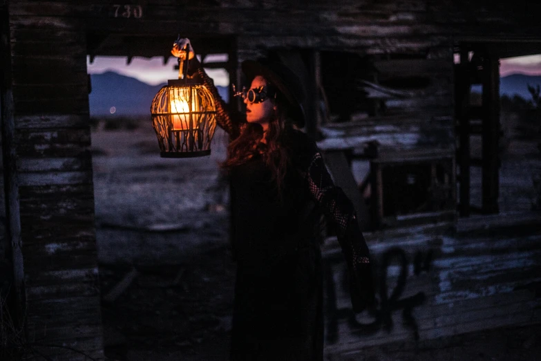 a woman standing in front of a wooden cabin holding a lantern, pexels contest winner, conceptual art, wearing apocalyptic clothes, emerging from her lamp, jenna barton, desert circus mystics