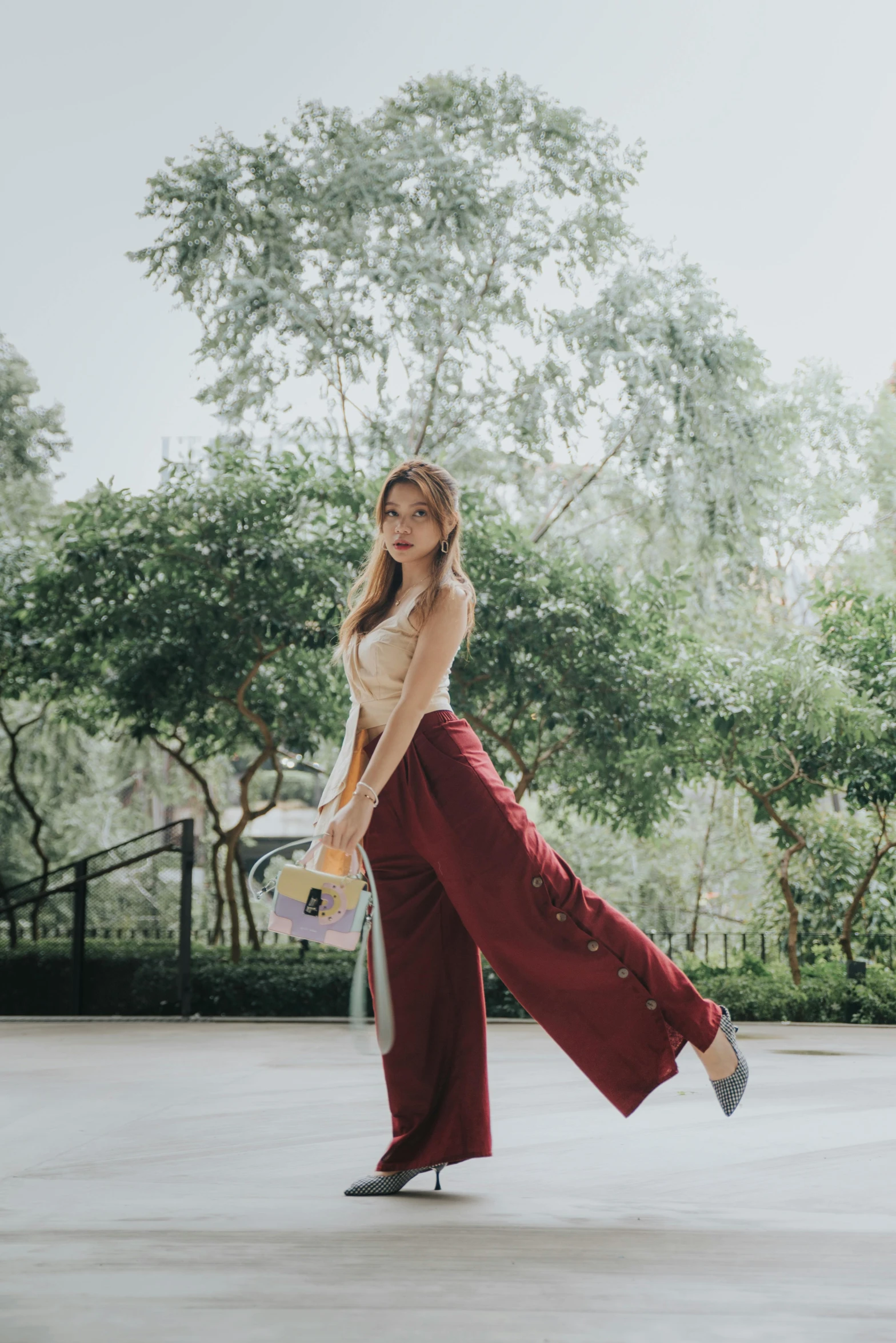 a woman standing on a skateboard in a parking lot, a colorized photo, inspired by Ni Duan, trending on pexels, maroon accents, large pants, standing in a botanical garden, wearing an elegant outfit