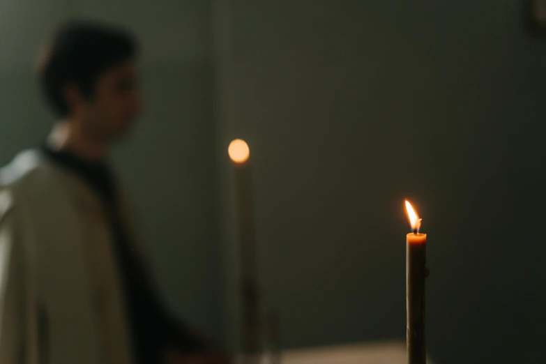 a man standing in front of a lit candle, unsplash, person in foreground, on a pale background, profile image, ignant