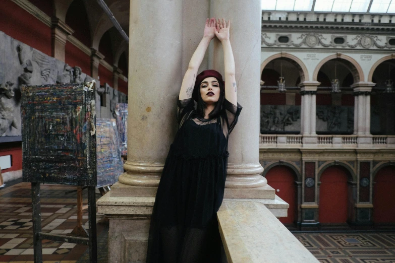 a woman in a black dress leaning against a pillar, inspired by Elsa Bleda, pexels contest winner, gothic art, inside a museum, black lipstick, queer woman, still from a music video
