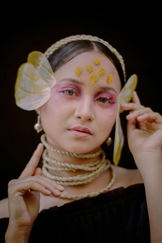 a woman with a butterfly on her face, a colorized photo, inspired by Sasha Putrya, trending on pexels, renaissance, assamese aesthetic, at a fashion shoot, wearing a pink head band, yellow makeup