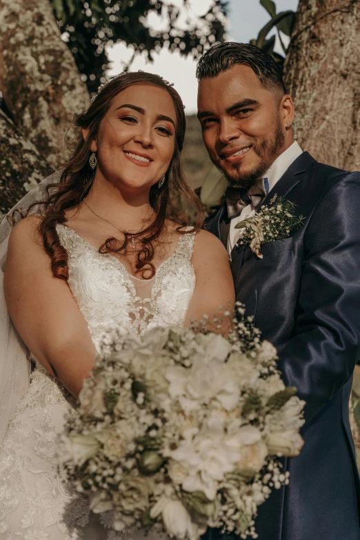 a bride and groom posing for a picture in front of a tree, te pae, close - up of the faces, high-quality photo, gif