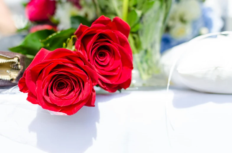 a couple of red roses sitting on top of a table, zoomed out, event photography, bright red, red