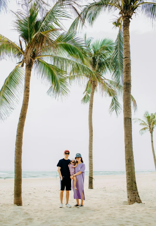 a man and woman standing next to each other on a beach, unsplash, minimalism, tree palms in background, ao dai, with a kid, wide angle”