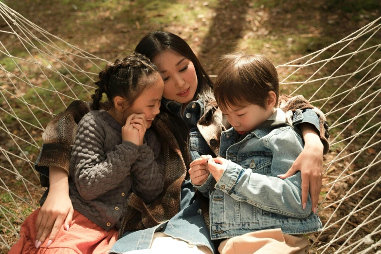 a woman and two children sitting in a hammock, inspired by Li Di, pexels, conceptual art, japanese live-action movie, denim, forest picnic, full frame image