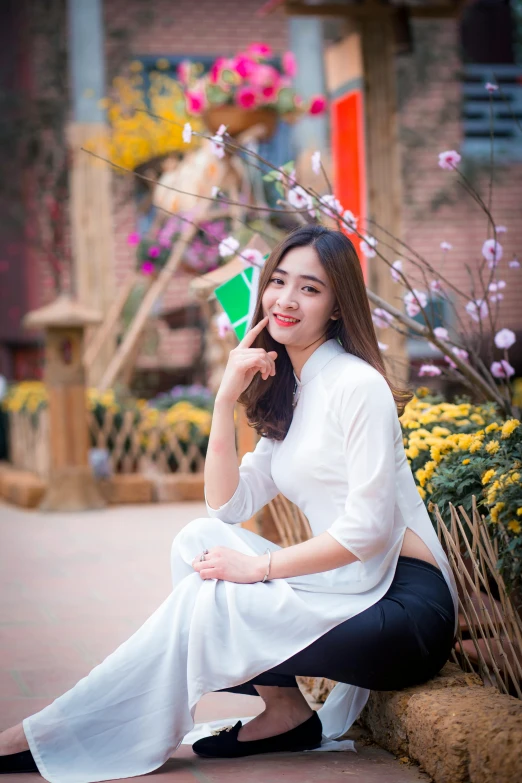 a woman sitting on the ground talking on a cell phone, a picture, inspired by Cui Bai, pexels contest winner, ao dai, young cute wan asian face, square, white sleeves