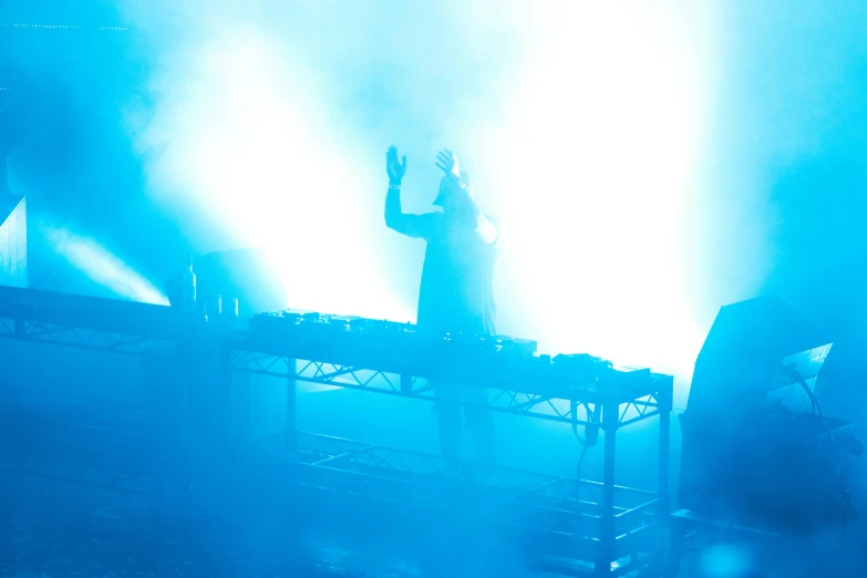 a man standing on top of a stage holding a microphone, light and space, djing with dj turntables, cyan fog, crystal castles, profile picture 1024px