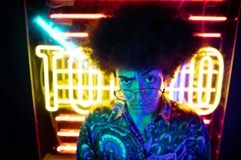 a person standing in front of a neon sign, a portrait, pexels, afrofuturism, with afro, reflecting light in a nightclub, actor, colorful retrofutur