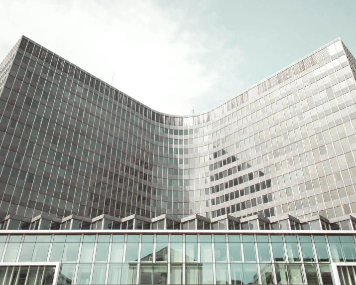 a very tall building with a lot of windows, inspired by David Chipperfield, pexels contest winner, brutalism, sunfaded, mies van der rohe, curvilinear architecture, view from ground