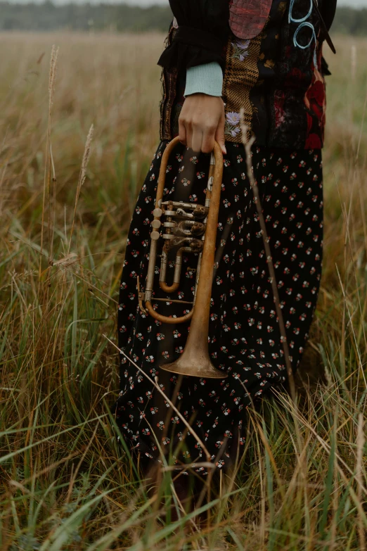 a woman standing in a field with a trumpet, unsplash, renaissance, detail shot, low quality photo, brass plated, gypsy