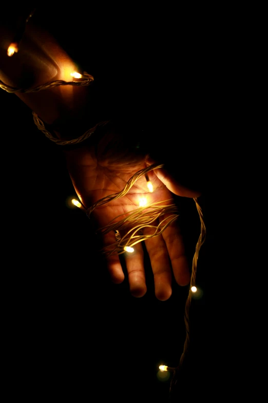 a hand holding a string of lights in the dark, by David Donaldson, ap art, multiple stories, stockphoto, broken