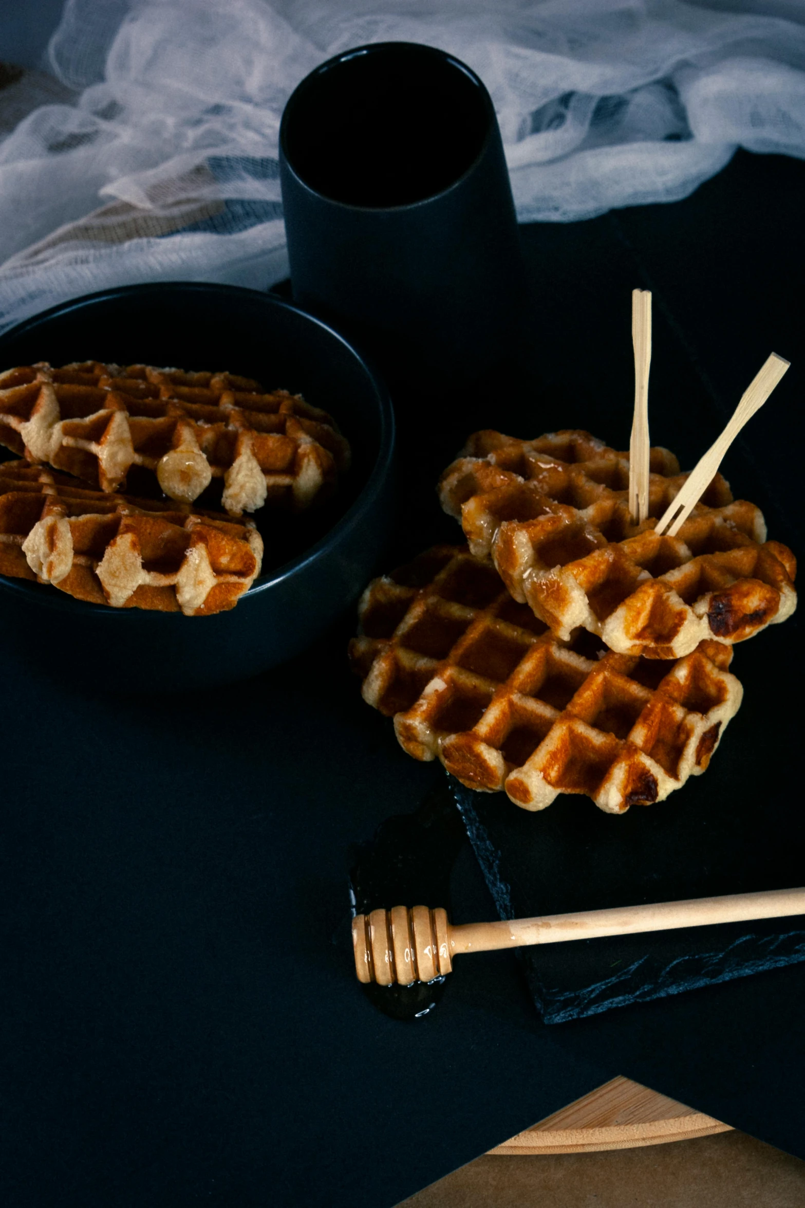 a couple of waffles sitting on top of a table, chopsticks, with a black background, 6 pack, thumbnail