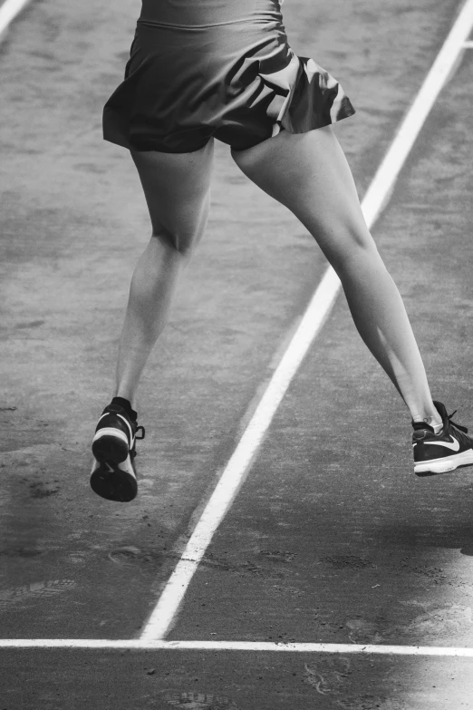 a woman swinging a tennis racquet on a tennis court, a black and white photo, unsplash, running shoes, thighs thighs thighs thighs, marathon race, running lights