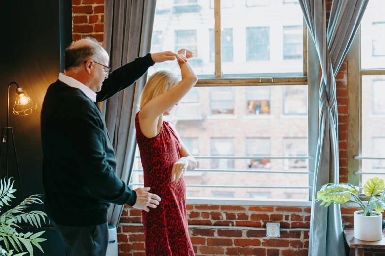 a man standing next to a woman in a red dress, unsplash, big window, gif, seattle, bright daylight indoor photo