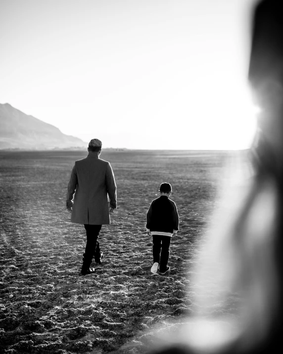 a black and white photo of a man and a child, by Sebastian Spreng, unsplash, walking away from the camera, lgbtq, mongolia, gentleman