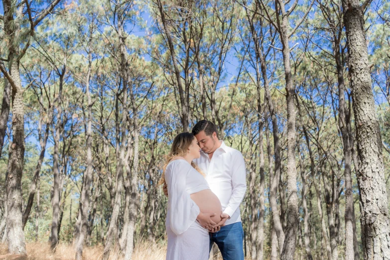 a pregnant woman standing next to a man in a forest, a photo, unsplash, happening, sweet acacia trees, avatar image, australian bush, bright white realistic