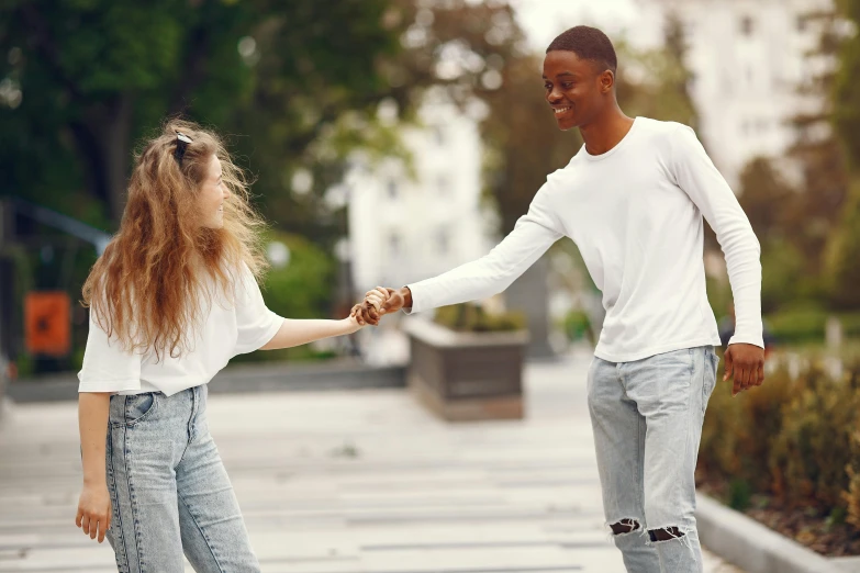 a man and a woman holding hands on a skateboard, trending on pexels, happening, black teenage boy, white trendy clothes, flirting smiling, windy day