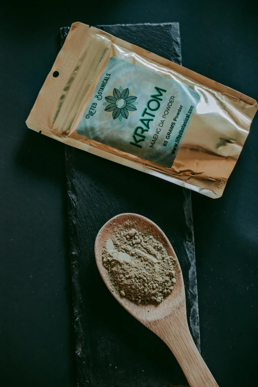 a wooden spoon sitting next to a bag of powder, gold green creature, atom, real photograph, hemp