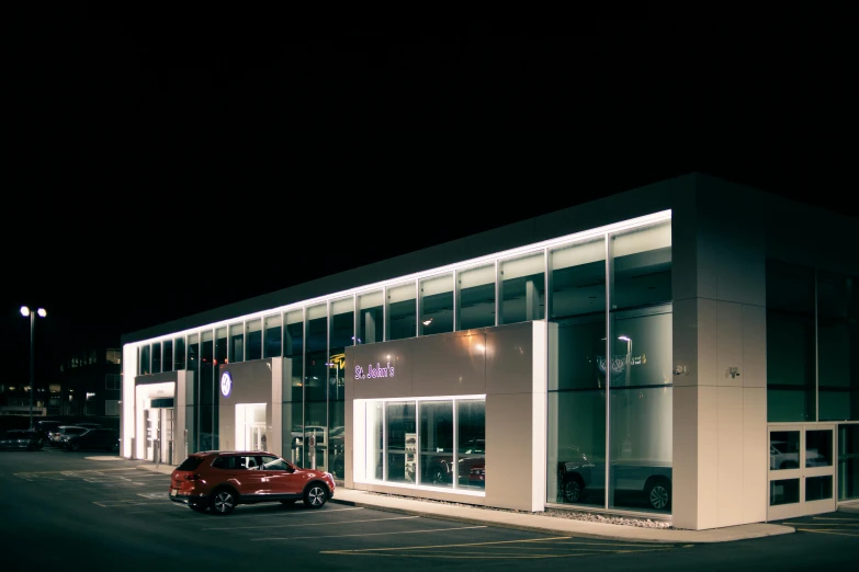 a red car parked in front of a building at night, at behance, renault, inside of an auto dealership, paul barson