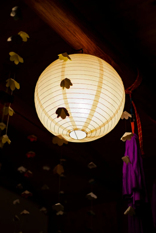 a lamp hanging from the ceiling in a dark room, inspired by Kanō Shōsenin, unsplash, mingei, paper decoration, yellow lanterns, taken in the late 2000s, soft bloom lighting