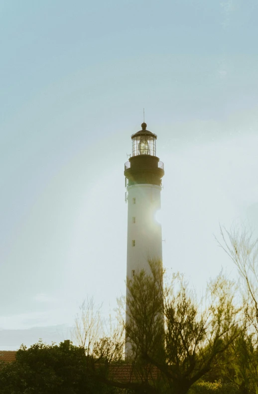 a light house sitting on top of a lush green field, a picture, unsplash, romanticism, lens flares. cinematic, tyndall rays, white, dramatic light 8 k