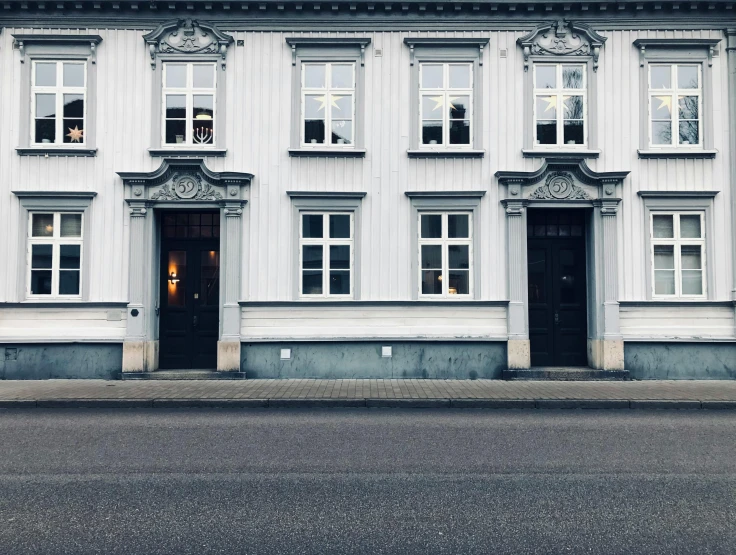 a large white building sitting on the side of a road, by Christen Købke, pexels contest winner, neoclassicism, house windows, grey, doorway, background image