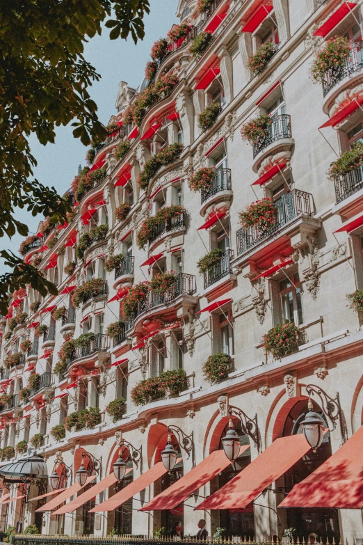 a red and white building with red awnings, a colorized photo, inspired by Gaston Anglade, unsplash contest winner, art nouveau, paris hotel style, hanging gardens, in spain, luxurious environment