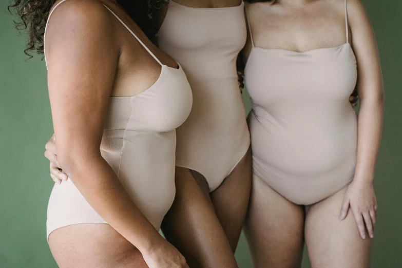 a couple of women standing next to each other, inspired by Vanessa Beecroft, unsplash, tans, three women, wearing leotard, neutral colours