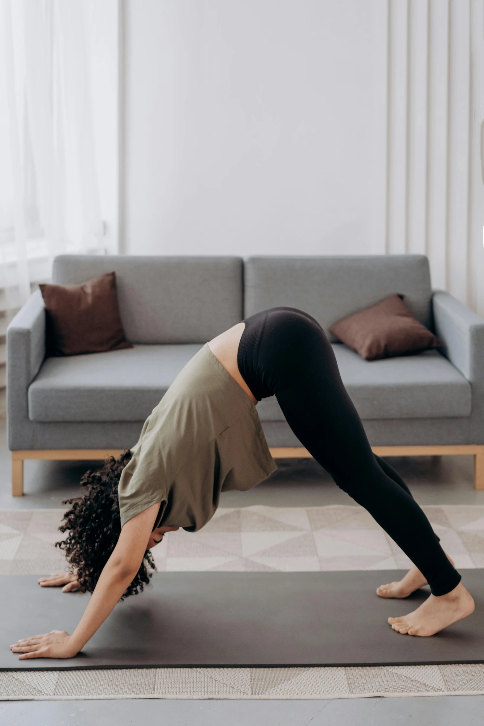 a woman doing a yoga pose in a living room, pexels contest winner, arabesque, bent over, cone shaped, dynamic active running pose, couch