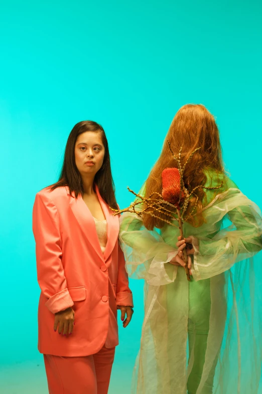 a couple of women standing next to each other, an album cover, by Olivia Peguero, renaissance, orange skin and long fiery hair, teal suit, photograph taken in 2 0 2 0, with organs