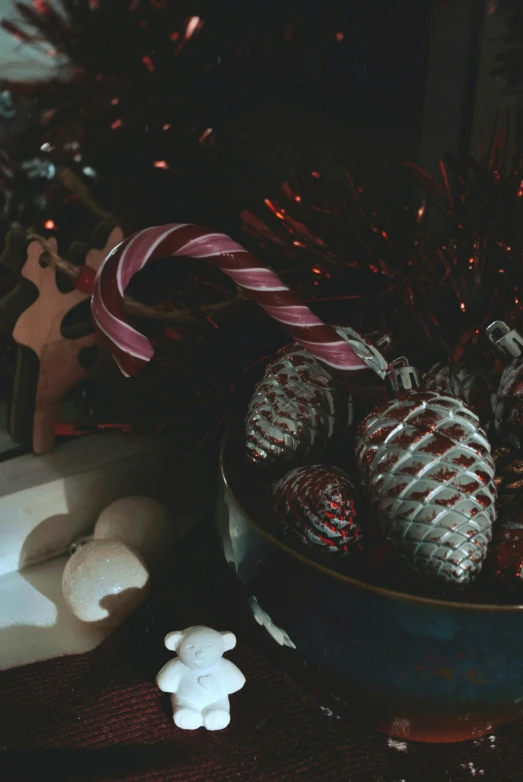 a bowl filled with candy canes next to a christmas tree, a still life, inspired by Elsa Bleda, pexels contest winner, pinecone, dark bright effect, medium format. soft light, silver ornaments