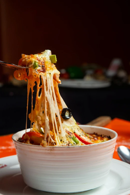 a close up of a bowl of food with a fork, by Robbie Trevino, cheese, spicy, overflowing, tall