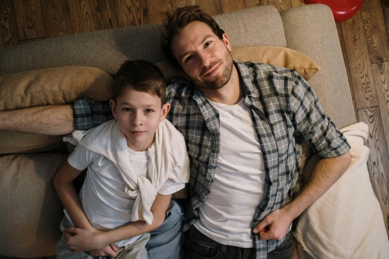 a man and a boy laying on a couch, by Adam Marczyński, pexels, looking the camera, avatar image, wearing casual clothes, fatherly