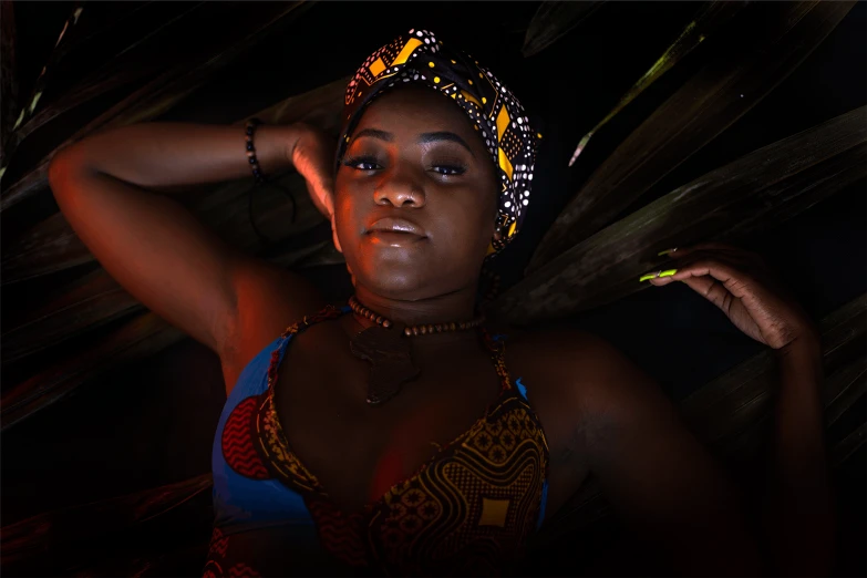 a woman in a colorful dress poses for a picture, a portrait, by Juan O'Gorman, pexels contest winner, afrofuturism, dark moody backlighting, sexy gaze, traditional photography, lush surroundings