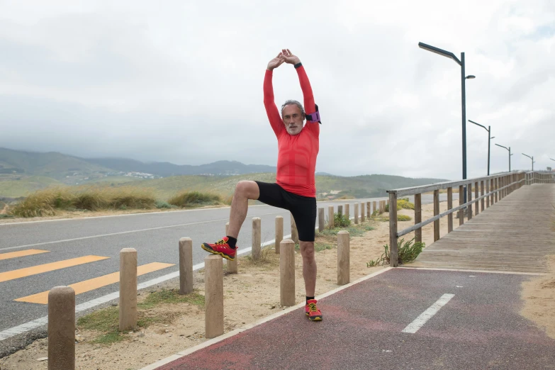 a man doing a handstand on the side of a road, by Breyten Breytenbach, avatar image, 5 5 yo, wearing fitness gear, near the sea