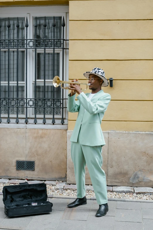 a man in a green suit playing a trumpet, by Ottó Baditz, trending on unsplash, wearing a light blue suit, on the street, maria borges, moody : : wes anderson
