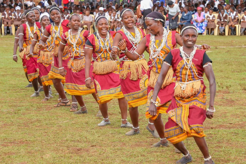 a group of people that are standing in the grass, by Ingrida Kadaka, pexels contest winner, hurufiyya, tribal dance, wearing a dress made of beads, people enjoying the show, emmanuel shiru