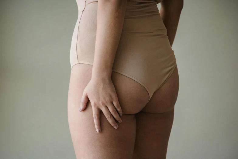 a close up of a person in a underwear, her skin is light brown, hand on hips, muted colour, mid body