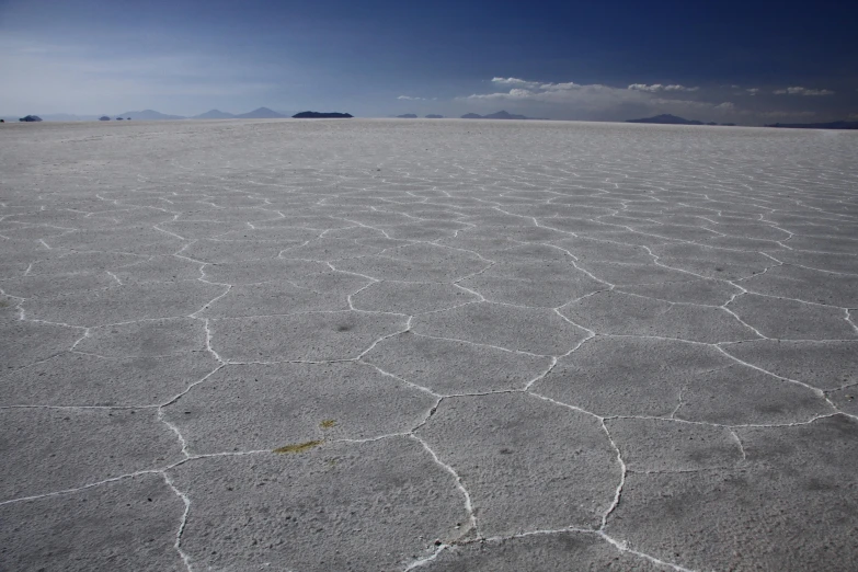 a desert landscape with a blue sky in the background, flickr, land art, at the salar de uyuni, background image, tar - like, grey