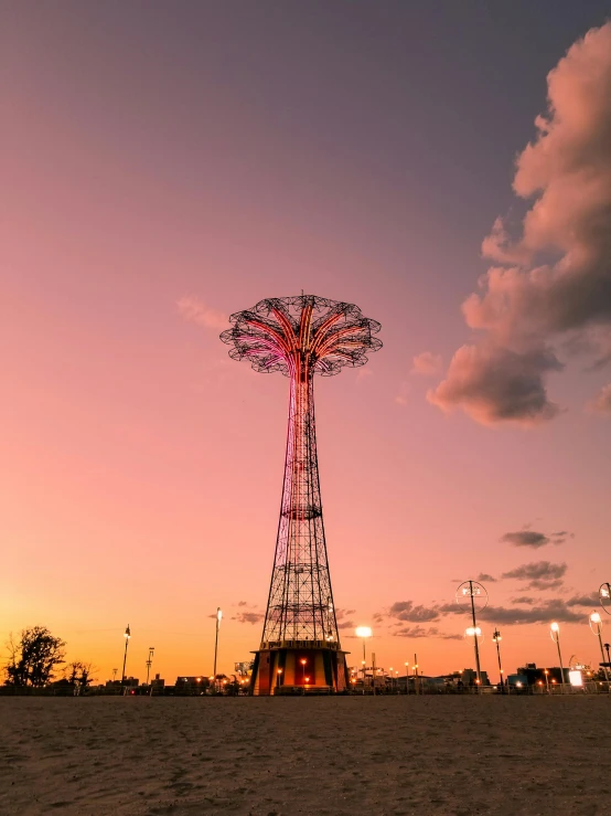 a ferris wheel sitting on top of a sandy beach, the sky is pink, looming over a city, jc park, 2022 photograph