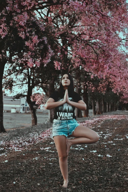 a woman standing in the middle of a park doing yoga, an album cover, by Lucia Peka, pexels contest winner, trees and flowers, casual pose, avatar image, religious