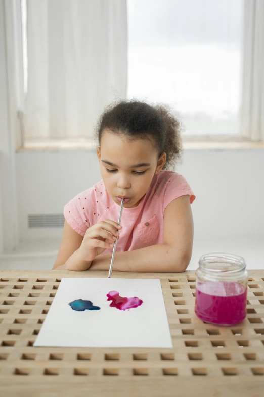 a little girl sitting at a table painting on a piece of paper, inspired by Helen Frankenthaler, pexels contest winner, blowing bubblegum, promo image, environmental shot, essence
