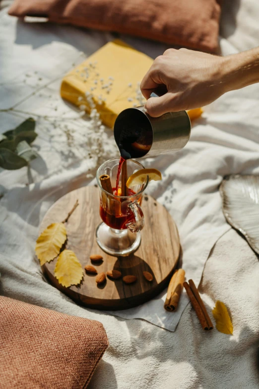 a person pouring something into a glass on a table, by Julia Pishtar, pexels contest winner, renaissance, the fall of summer, wood cups, recipe, warm coloured