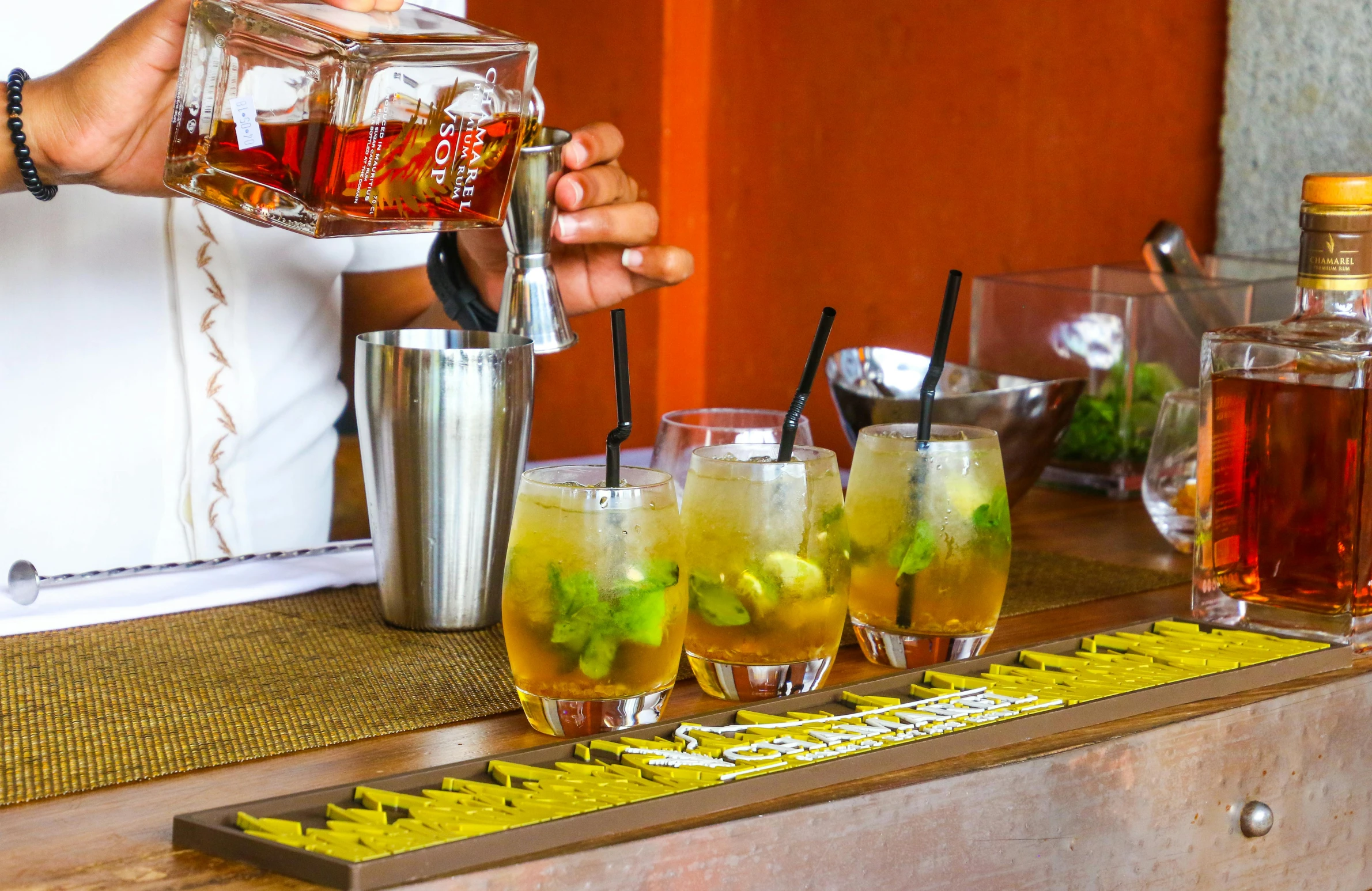 a bartender pours a drink at a bar, pexels, process art, assam tea garden setting, square, tropical style, 6 pack