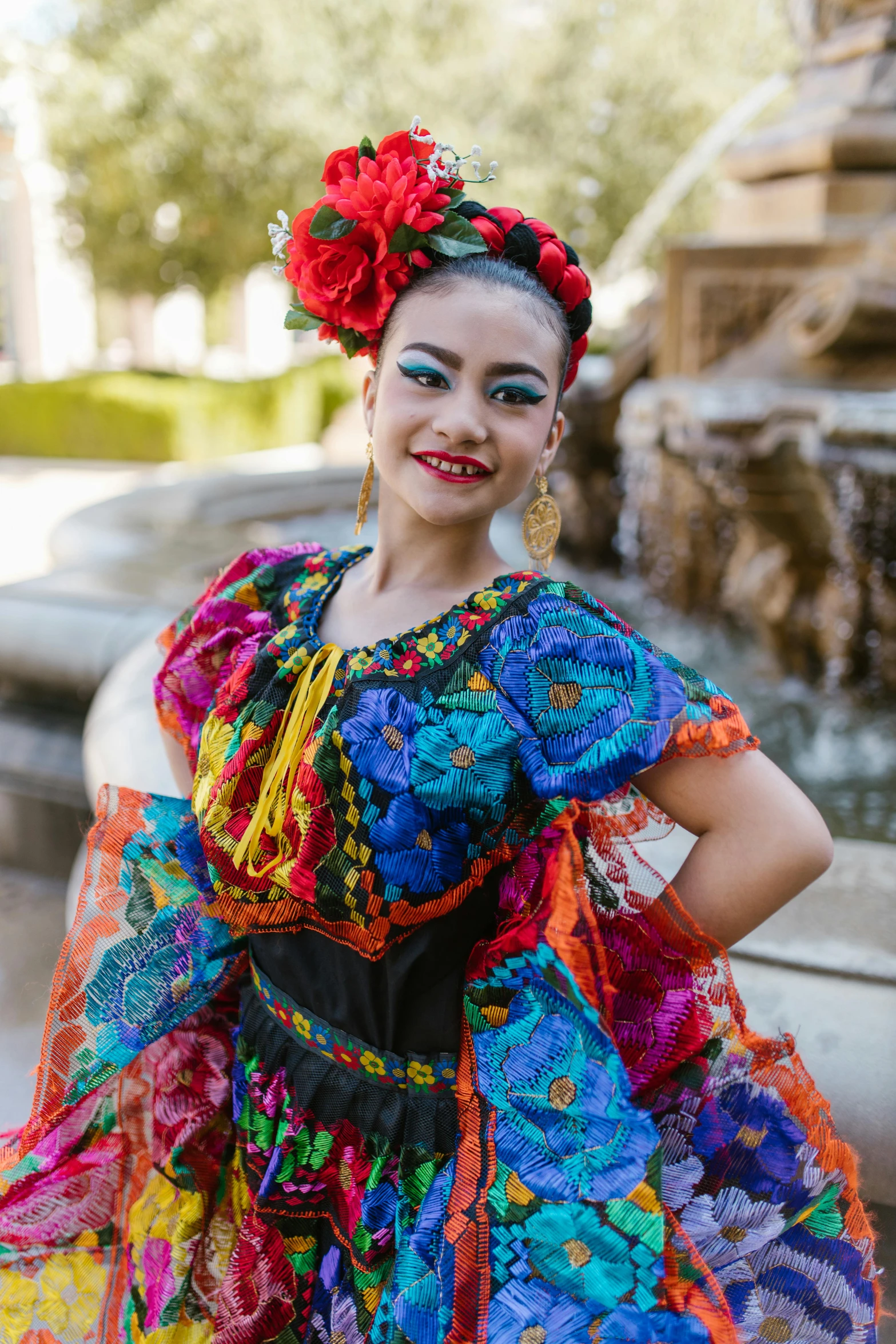 a woman in a colorful dress posing in front of a fountain, inspired by Frida Kahlo, diverse costumes, slide show, isabela moner, square