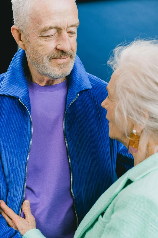 a man and a woman standing next to each other, a portrait, trending on pexels, blue jacket, dementia, profile image, colourful clothing